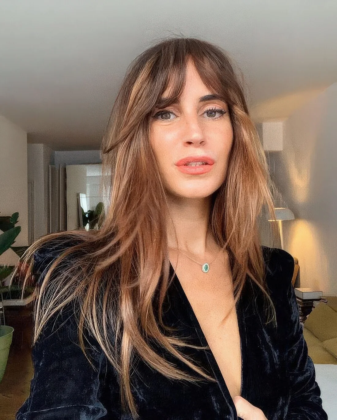 Long light brunette hair with blonde and caramel balayage and bottleneck bangs.