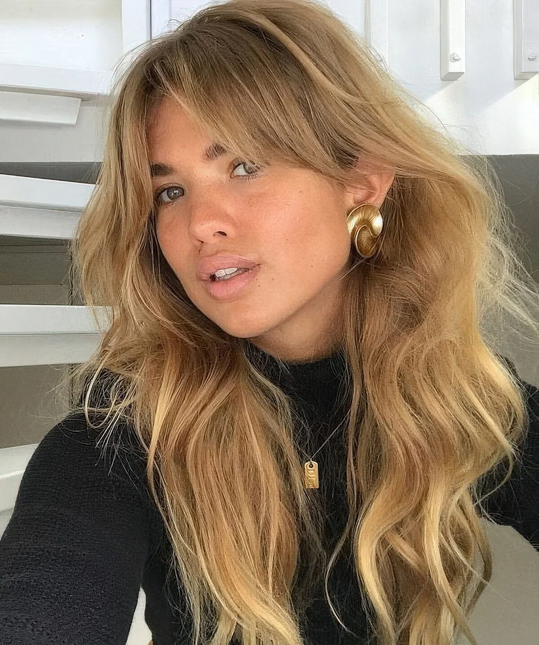 Long wavy and dimensional blonde hair with bottleneck bangs and waves.