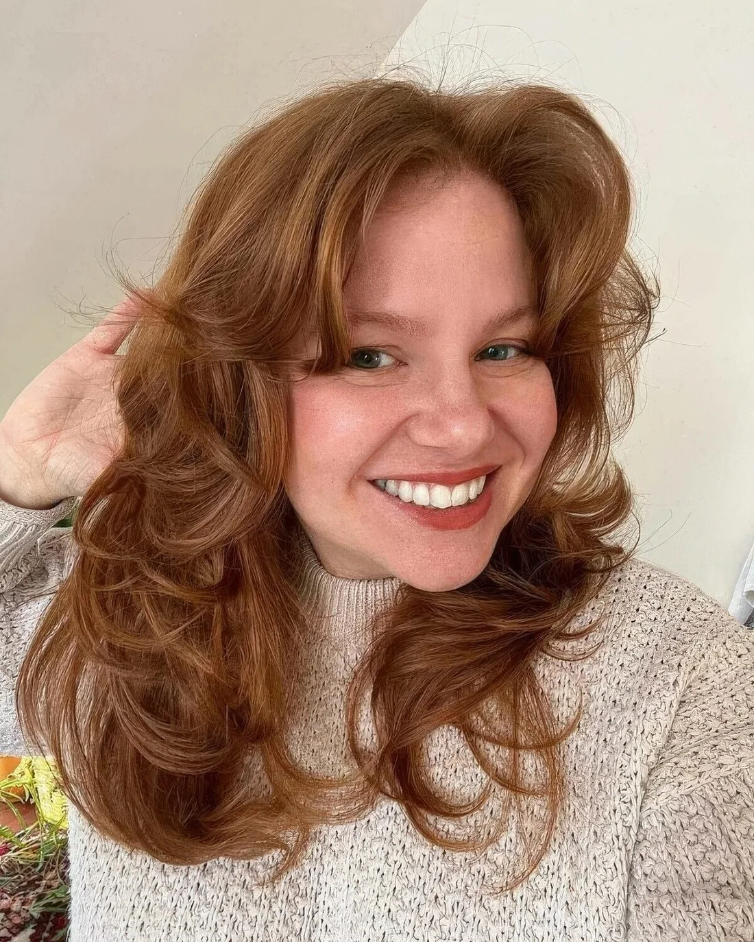 Long cinnamon haircut with curls and soft curtain bangs.