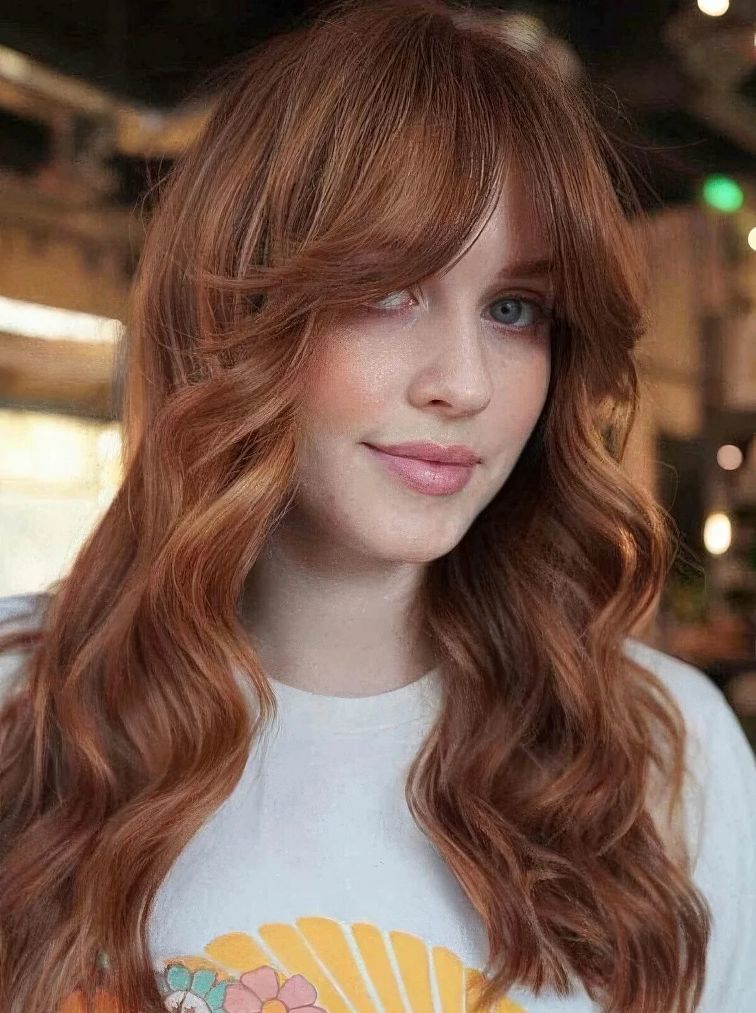 Long ginger hair with shaggy layers and waves plus a soft curtain fringe that accents the eyes.