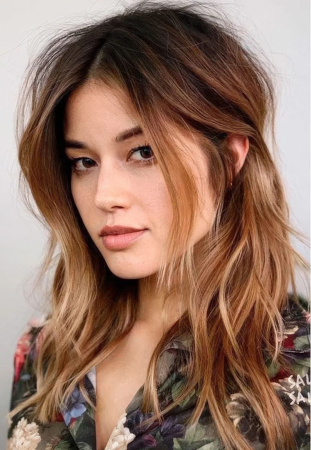 Dark brown root plus ombre caramel ends and messy waves plus layered bangs.