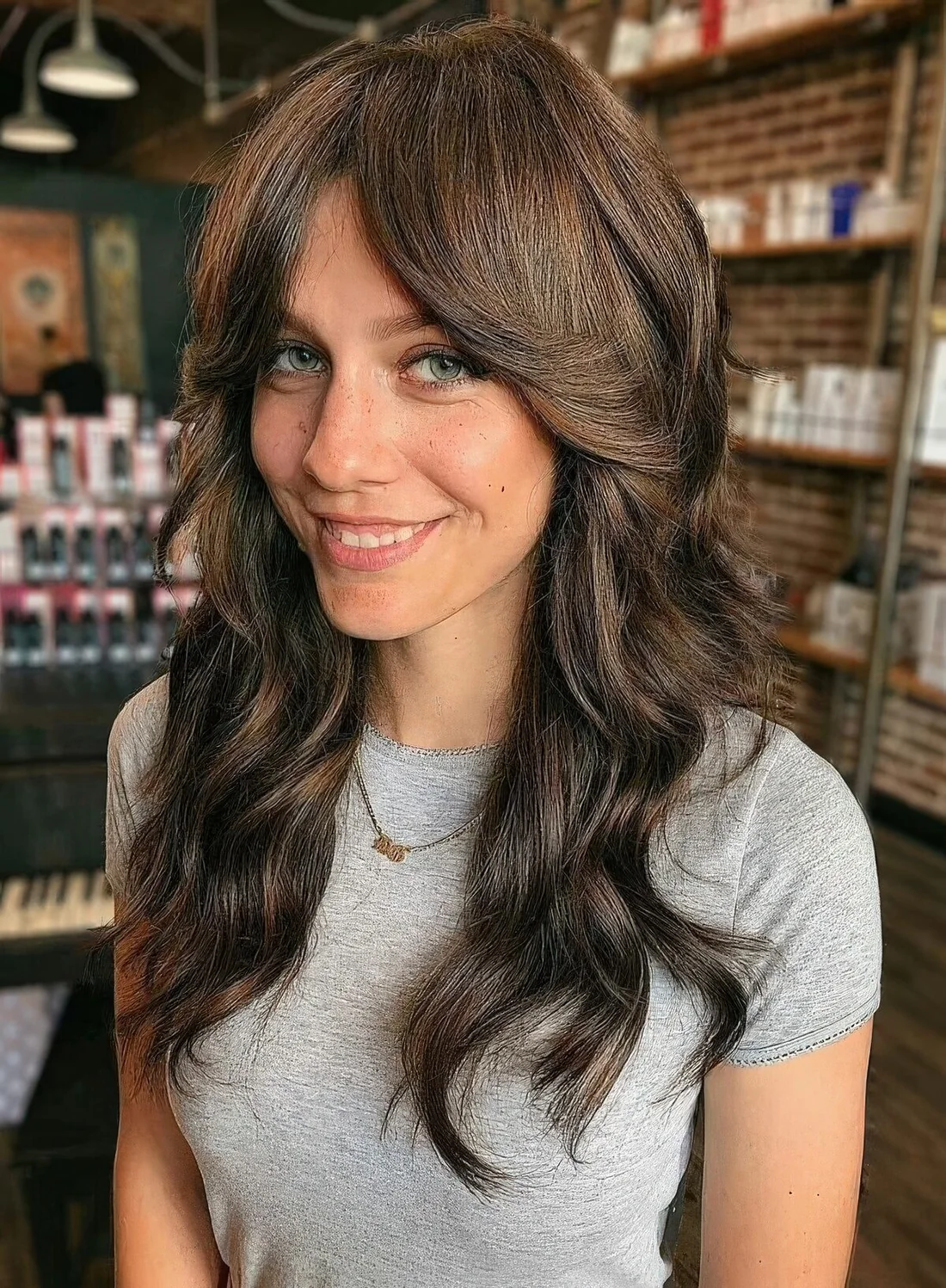 Long dark brown shaggy hair with long curtain bangs and dimensional highlights.
