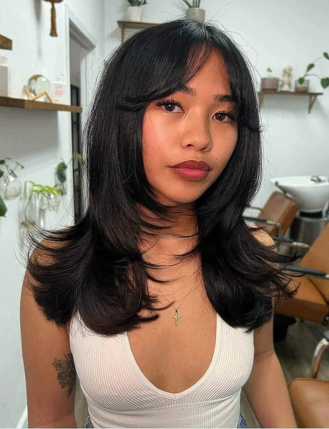 Long black hair with a shaggy touch, face-framing layers and soft curtain bangs.