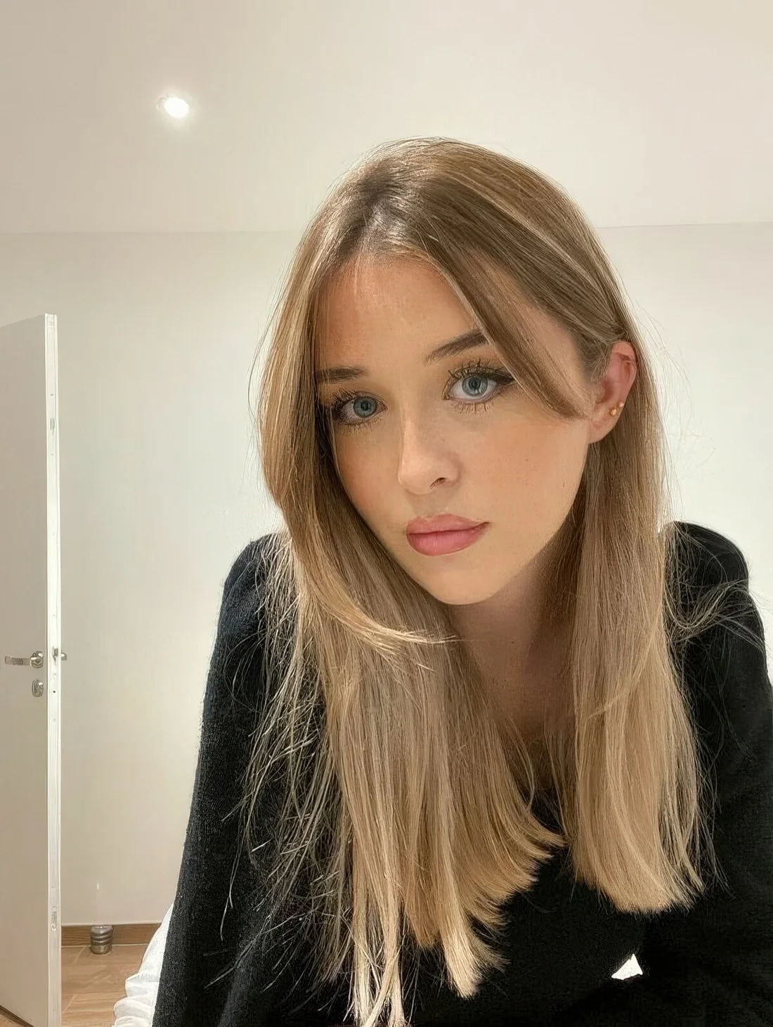Long blonde hair with balayage and long curtain bangs.