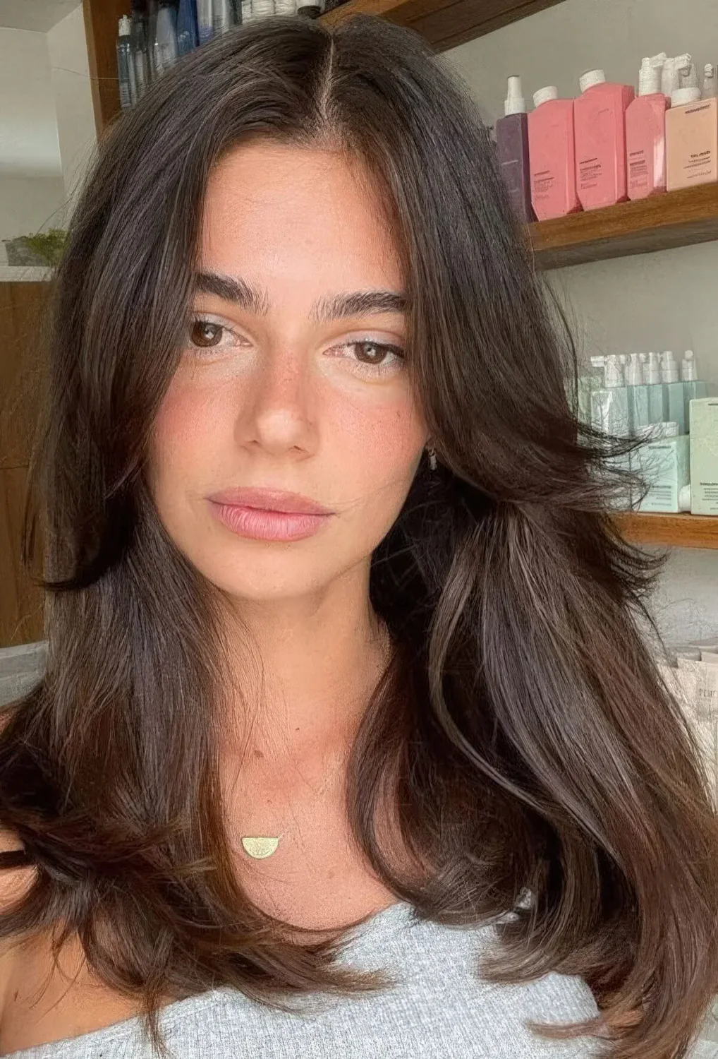 Long dark brown hair with curtain bangs and center part.