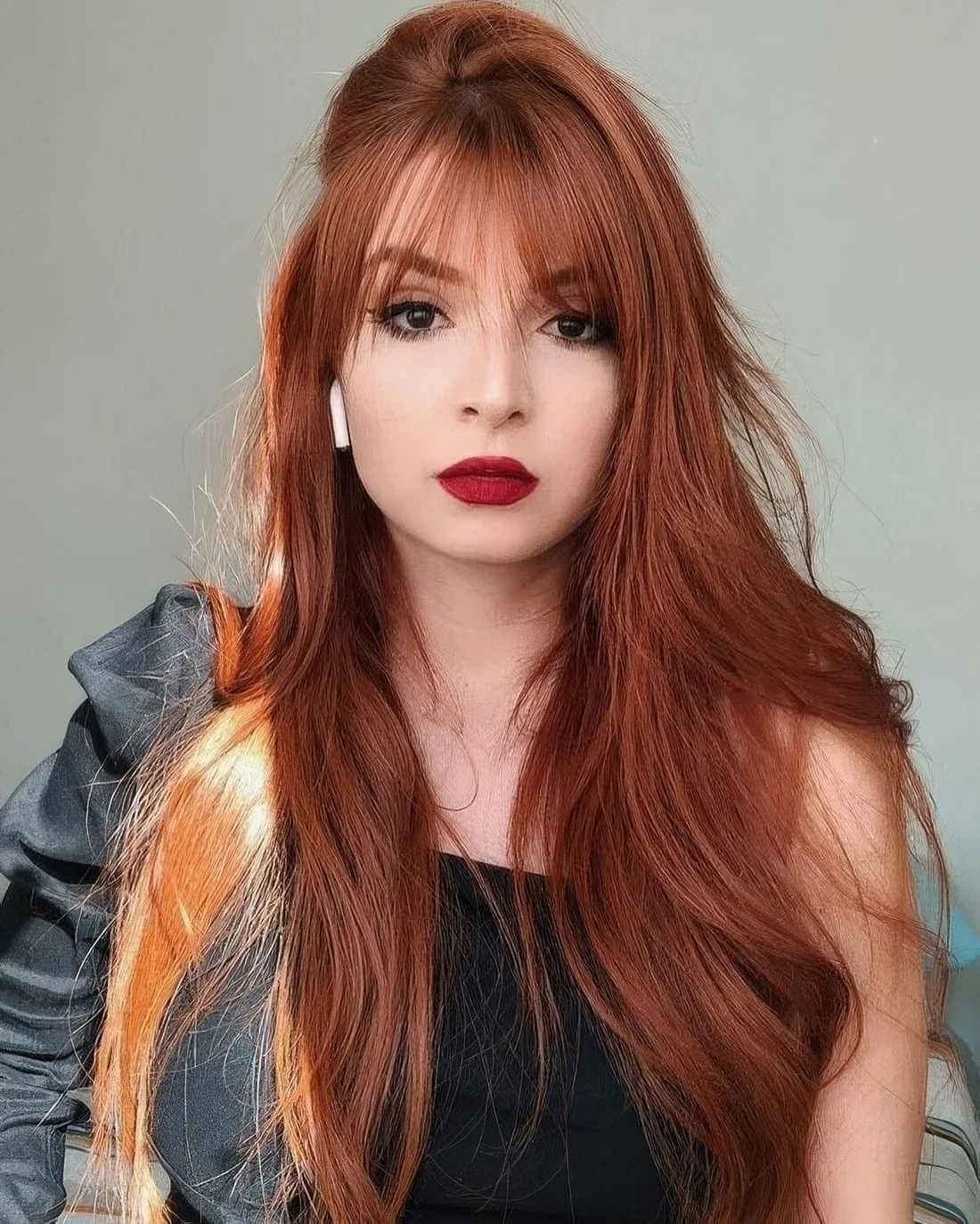 Long red hair with wispy bangs for subtle face-framing and to make a delicate touch with this hair color.