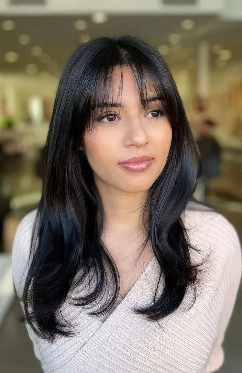 Long black hair with wispy bangs and center part.