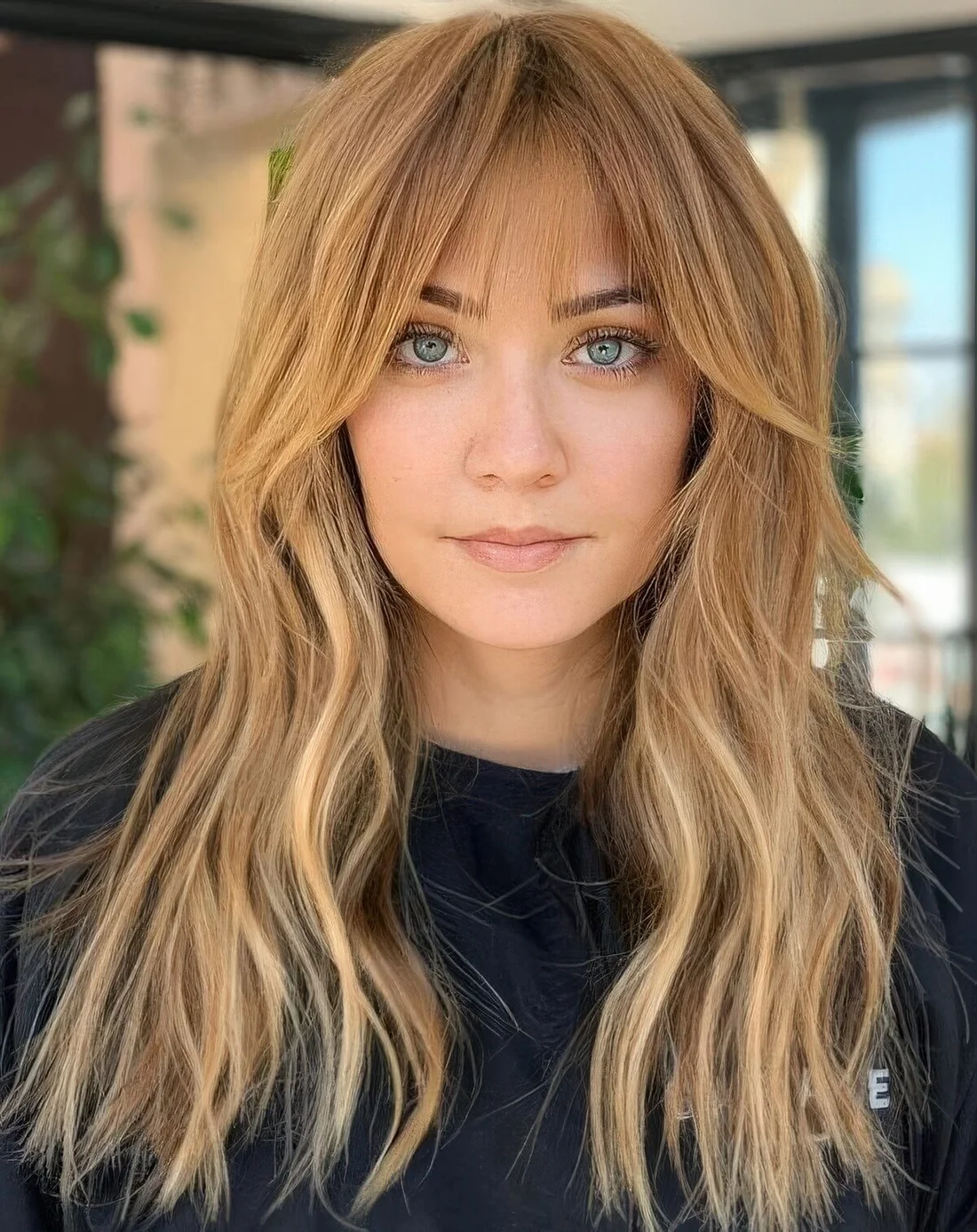 Long caramel hair with blonde balayage and with layered bangs curtain and wispy ones for a subtle touch.