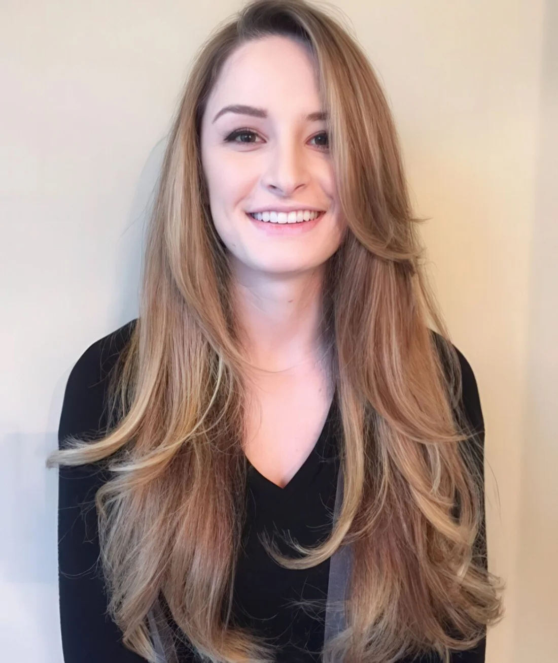 Long layered haircut with side bangs and blonde balayage for a chic look.