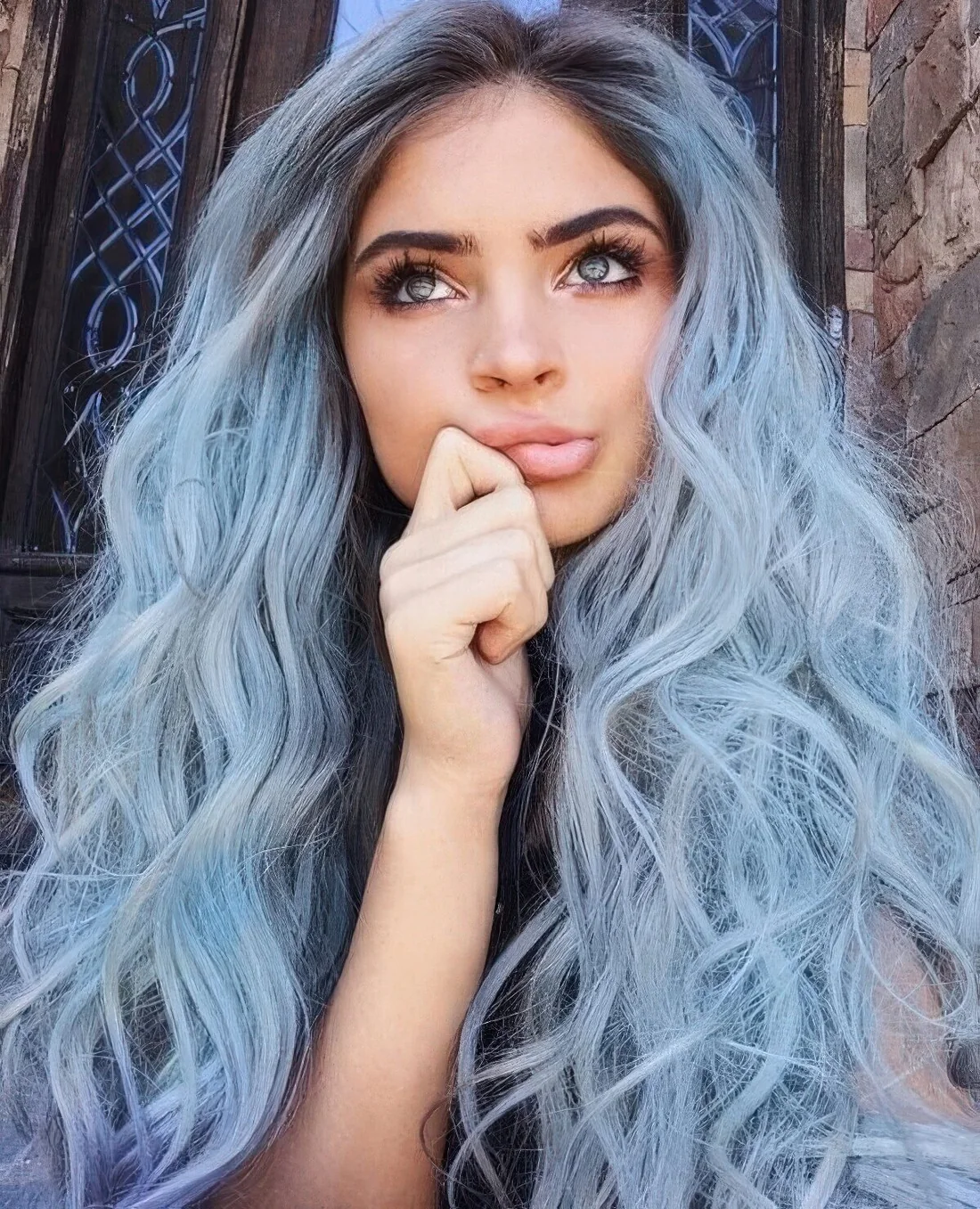 Long pastel blue hair with a darker root and waves.