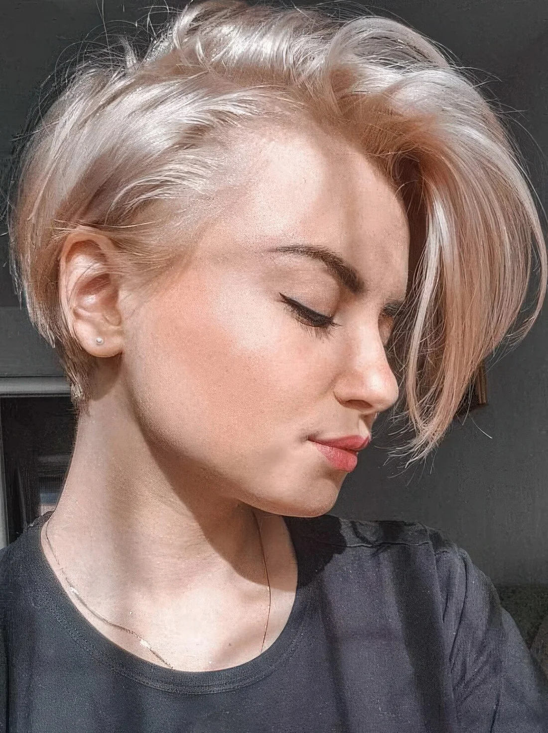 Long side pixie haircut in a platinum blonde shade.