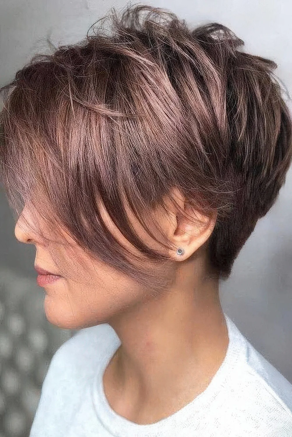 Shiny mauve pixie haircut with a long fringe.