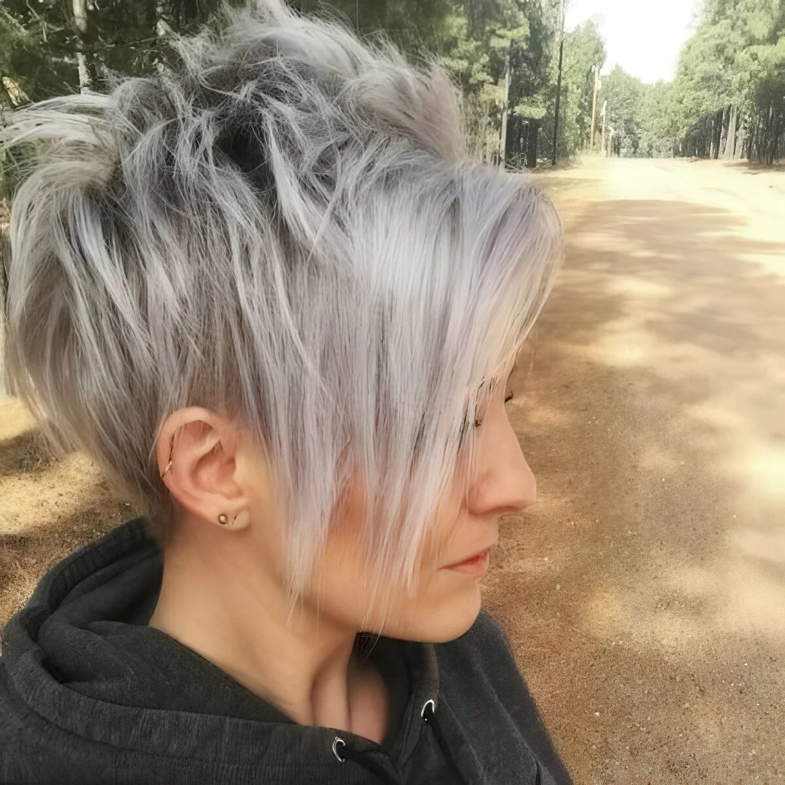 Longer pixie haircut with bangs with trendy grey balayage.