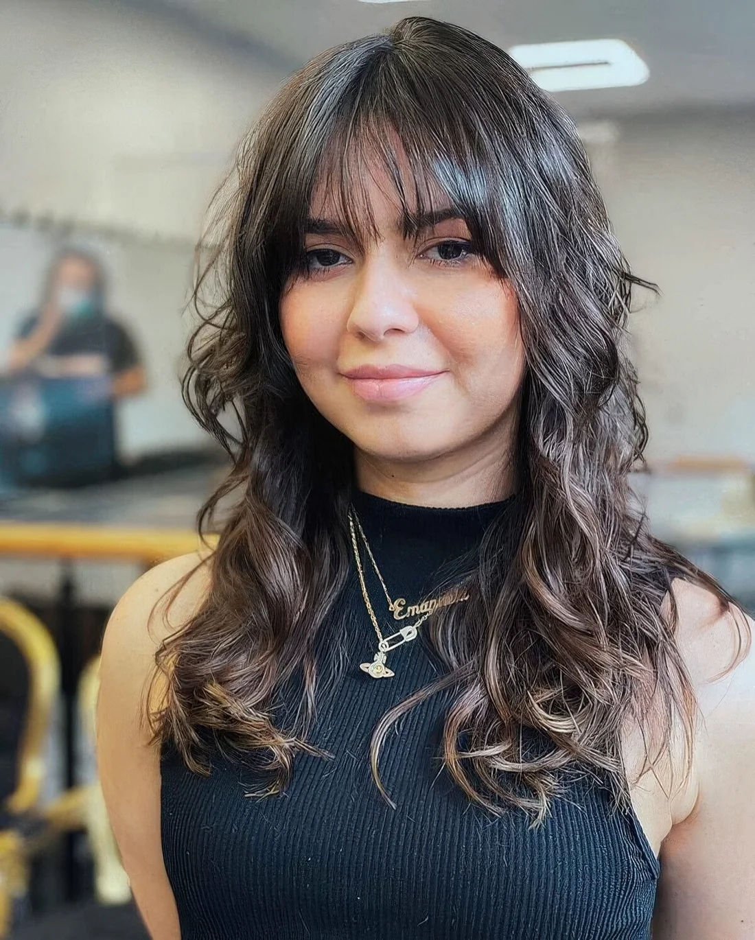 Dark brown long wolf haircut with wispy bangs and curls down that soften the look and make it girlish.