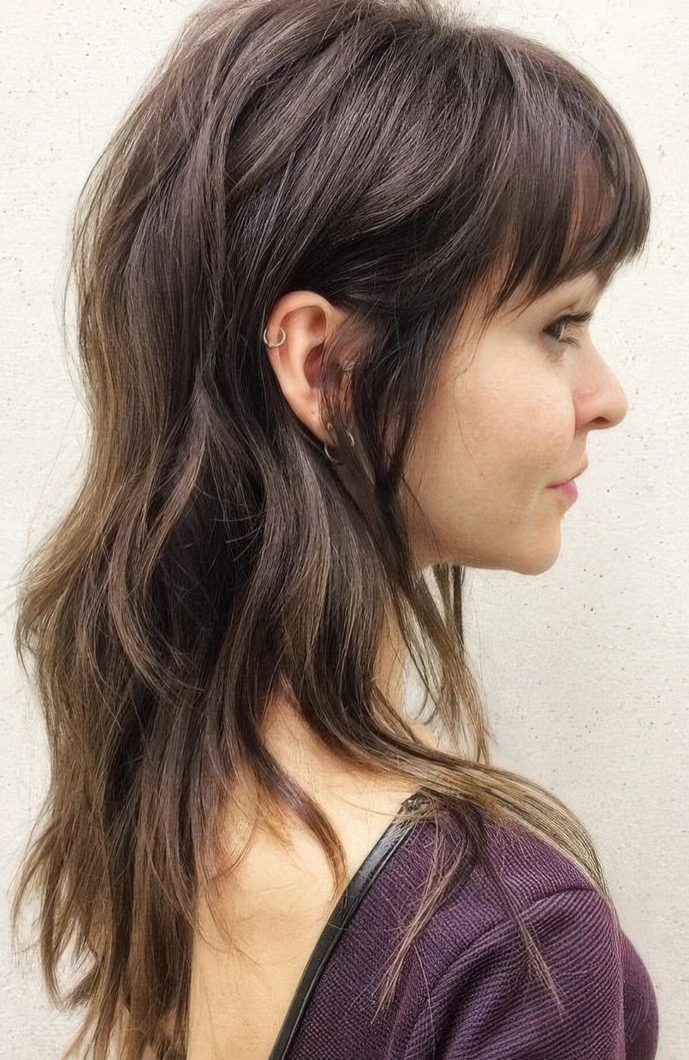 Dark brown wolf cut with bangs, long layers.