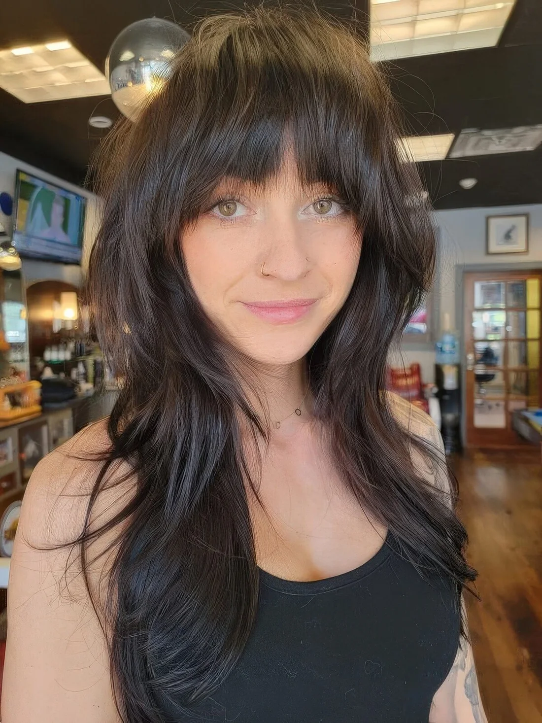 Dark brunette long wolf cut with blunt bangs, waves down.