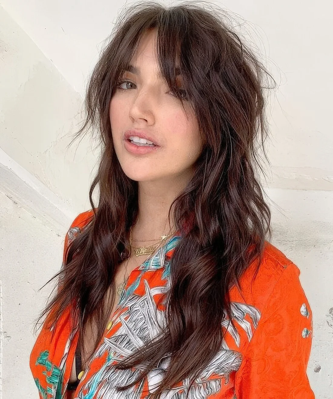 Dark brunette long wolf haircut with bottleneck bangs, waves down and volume.