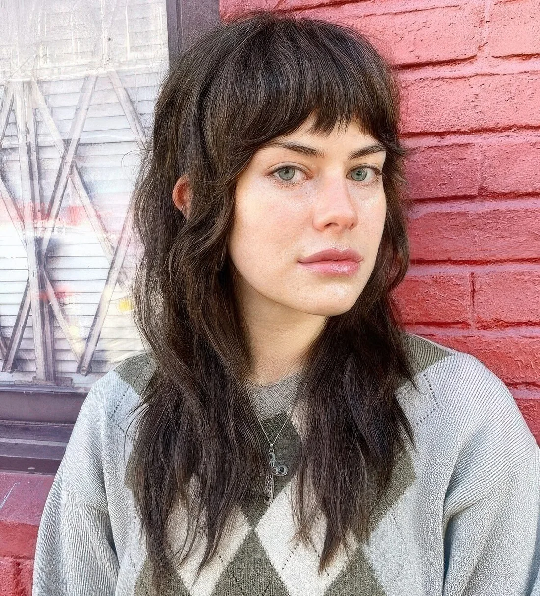 Dark brunette wolf haircut with blunt bangs and waves down.