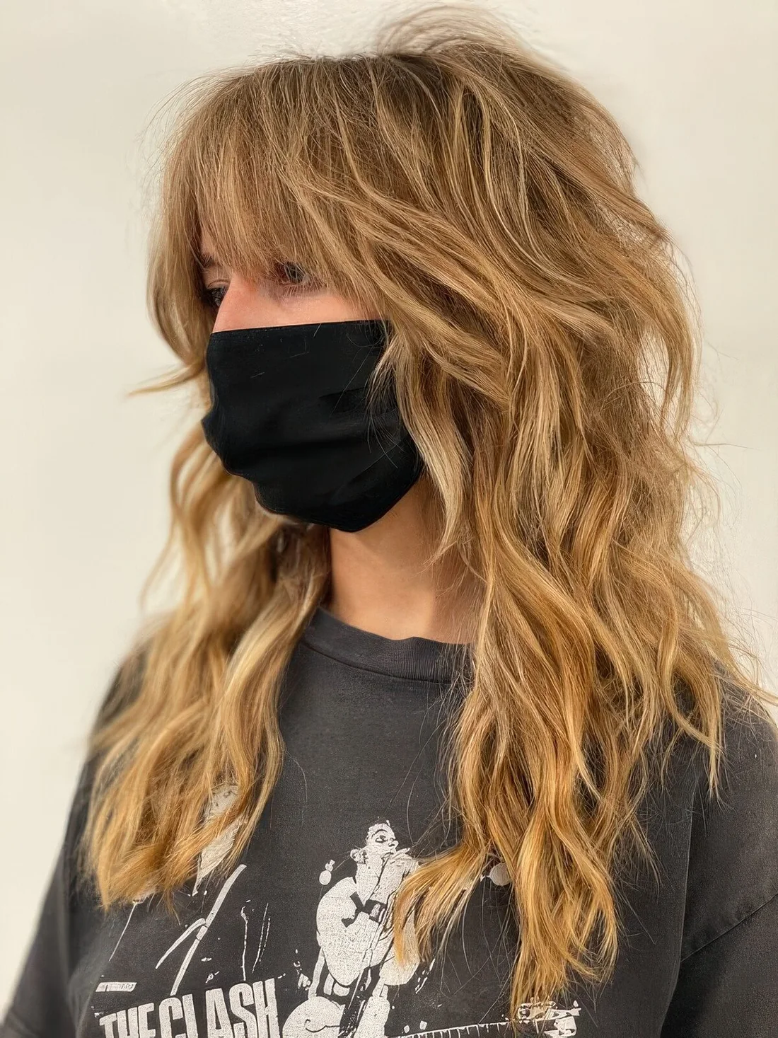 Honey blonde wolf cut with bottleneck bangs and waves down plus messy texture.