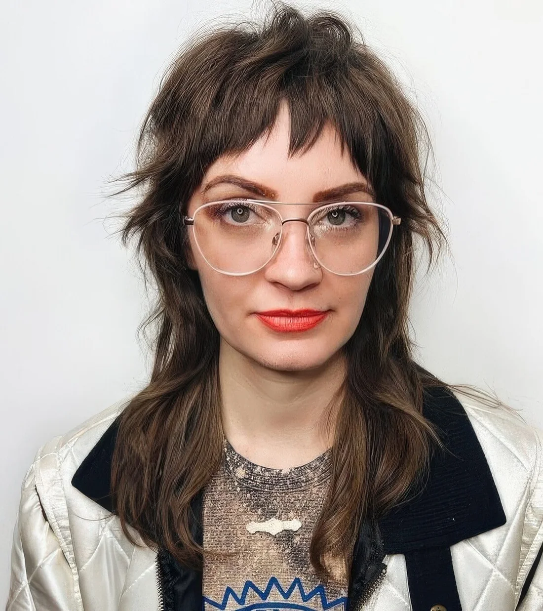 Long brown wolf cut with bottleneck bangs and layers.
