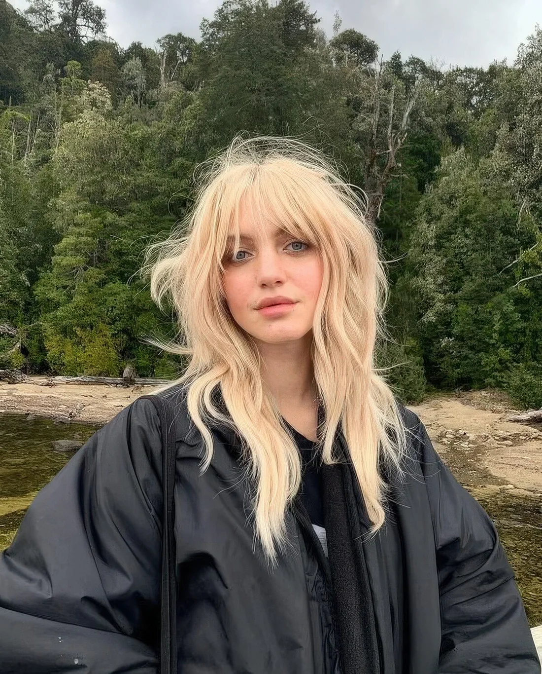 Shaggy long wolf cut done in a warm shade of blonde, with outgrown and bottleneck bangs, with long layers.