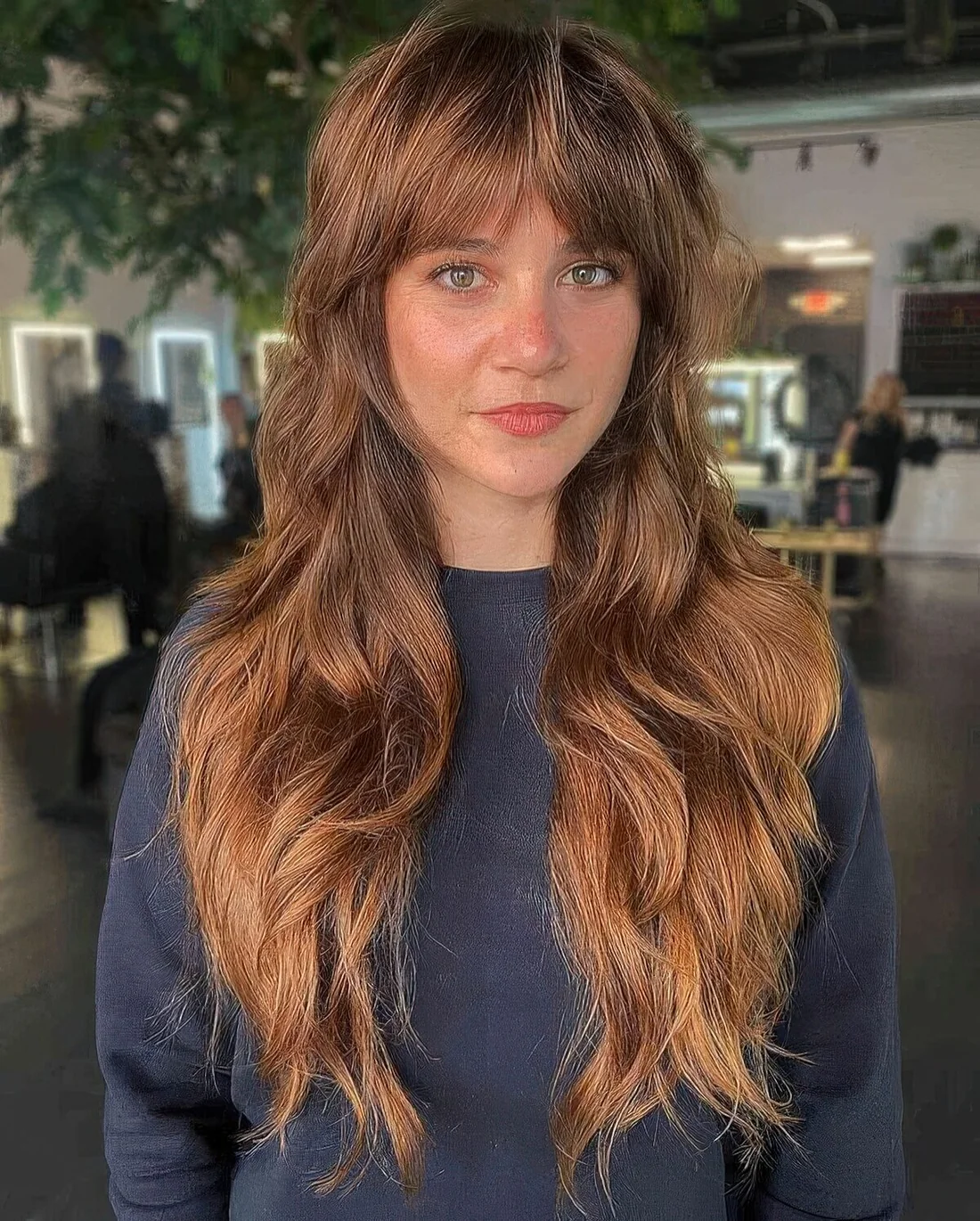 Ginger brunette wolf cut with curtain bangs, waves and volume.