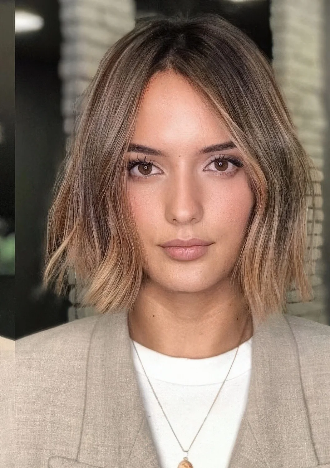 Brown bob with darker root and caramel and gold balayage, with irregular parting and slight waves.