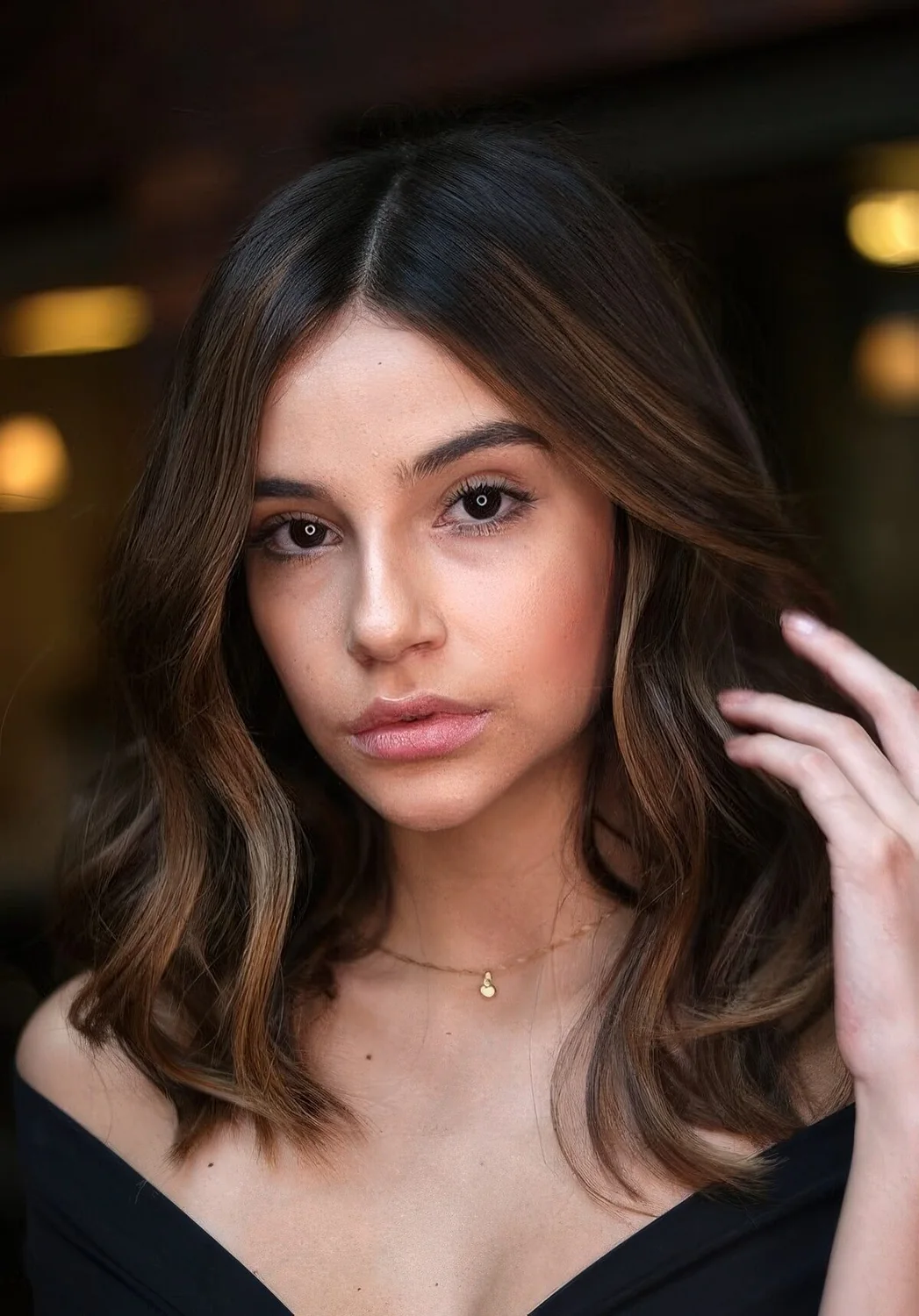 Almost black wavy long bob with super delicate and subtle caramel highlights including face-framing ones for a bolder look.