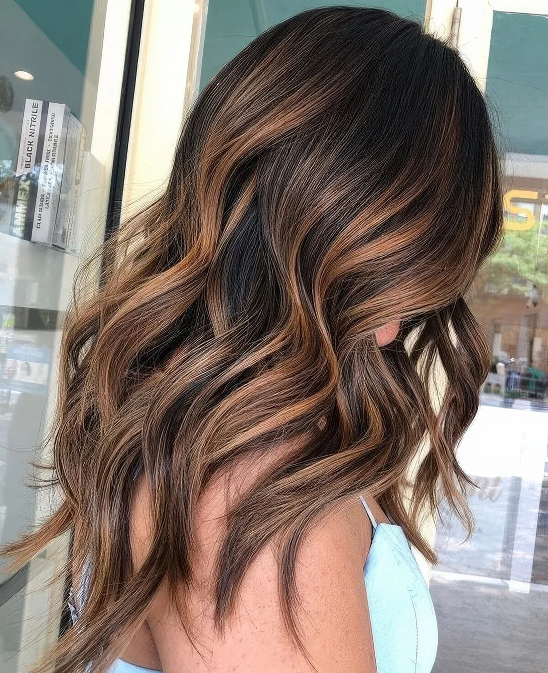 Long dark brown hair with rich caramel highlights and waves for a more eye catchy and cool look.