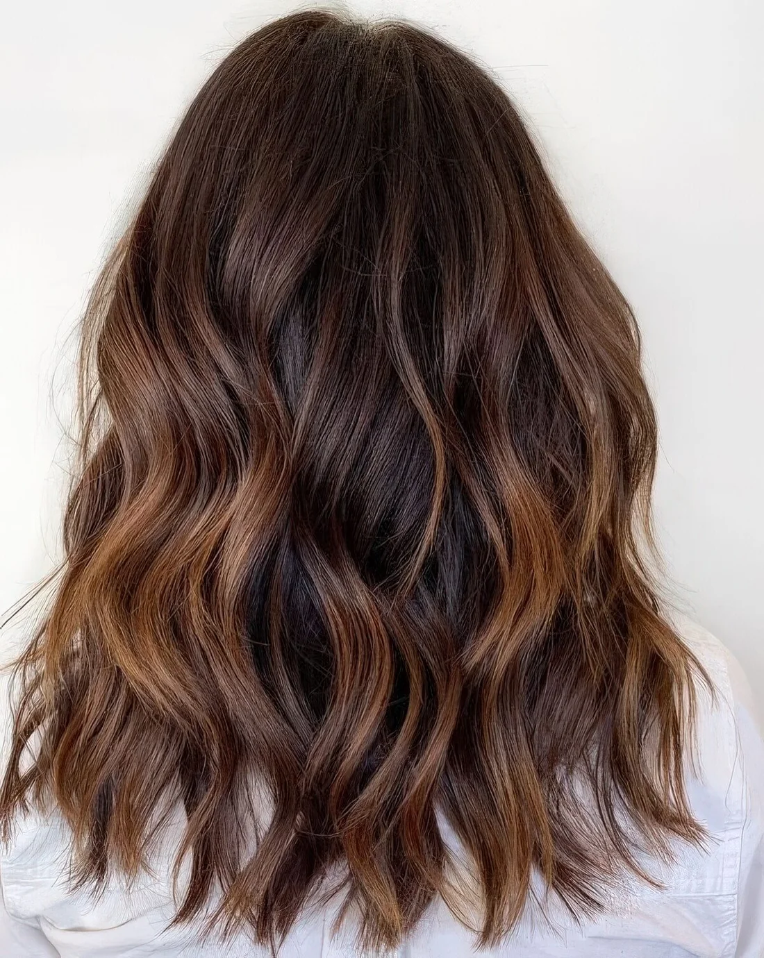 Chocolate brown wavy hair with very subtle touches of caramel balayage.