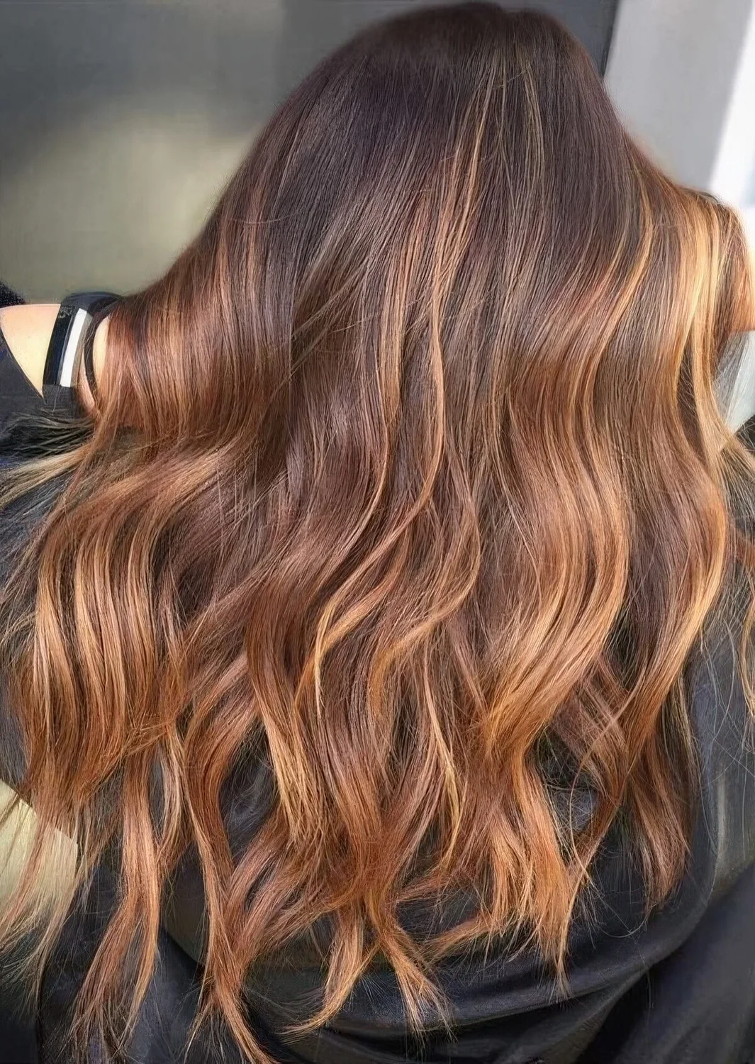 Dark auburn hair with waves and lovely bold caramel balayage for a catchy and chic look just wows.