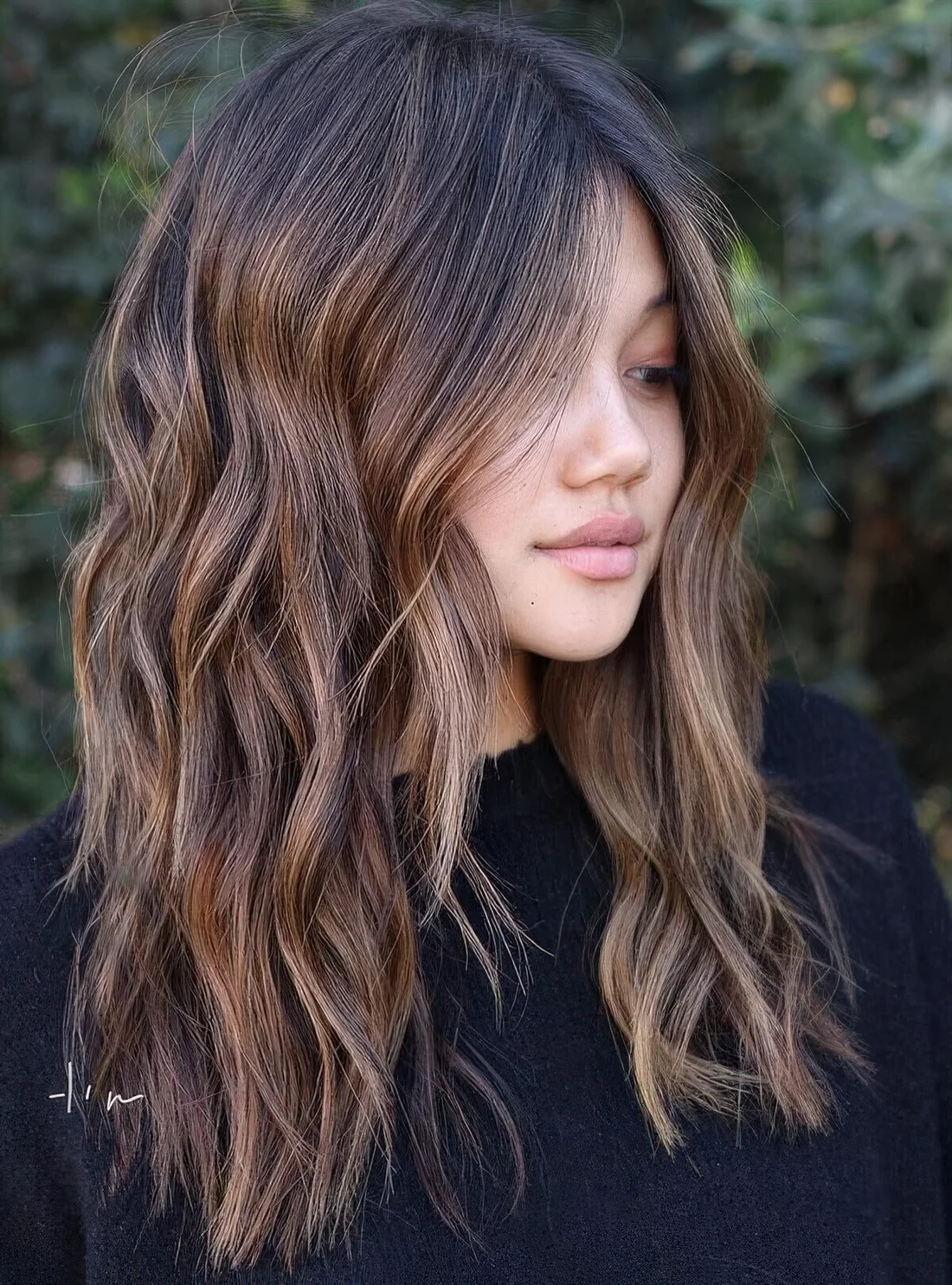 Dark brown wavy hair with caramel balayage and center part.