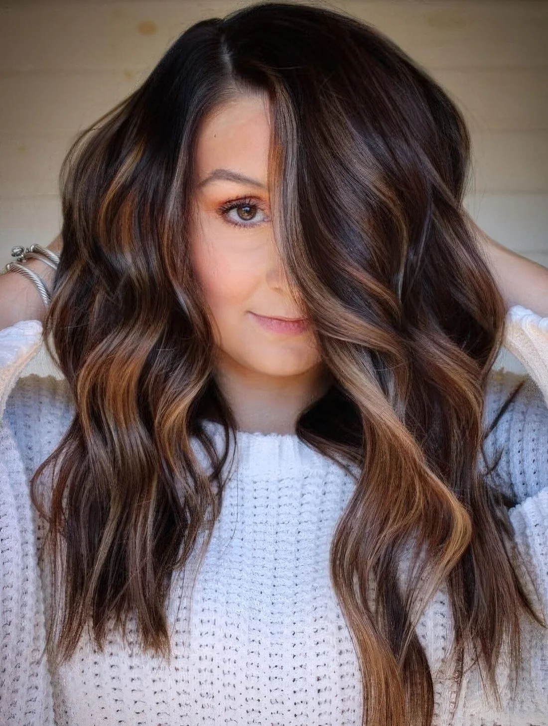 Dark chestnut brown hair with waves and with delicate and subtle caramel balayage that highlights the chestnut shade and.