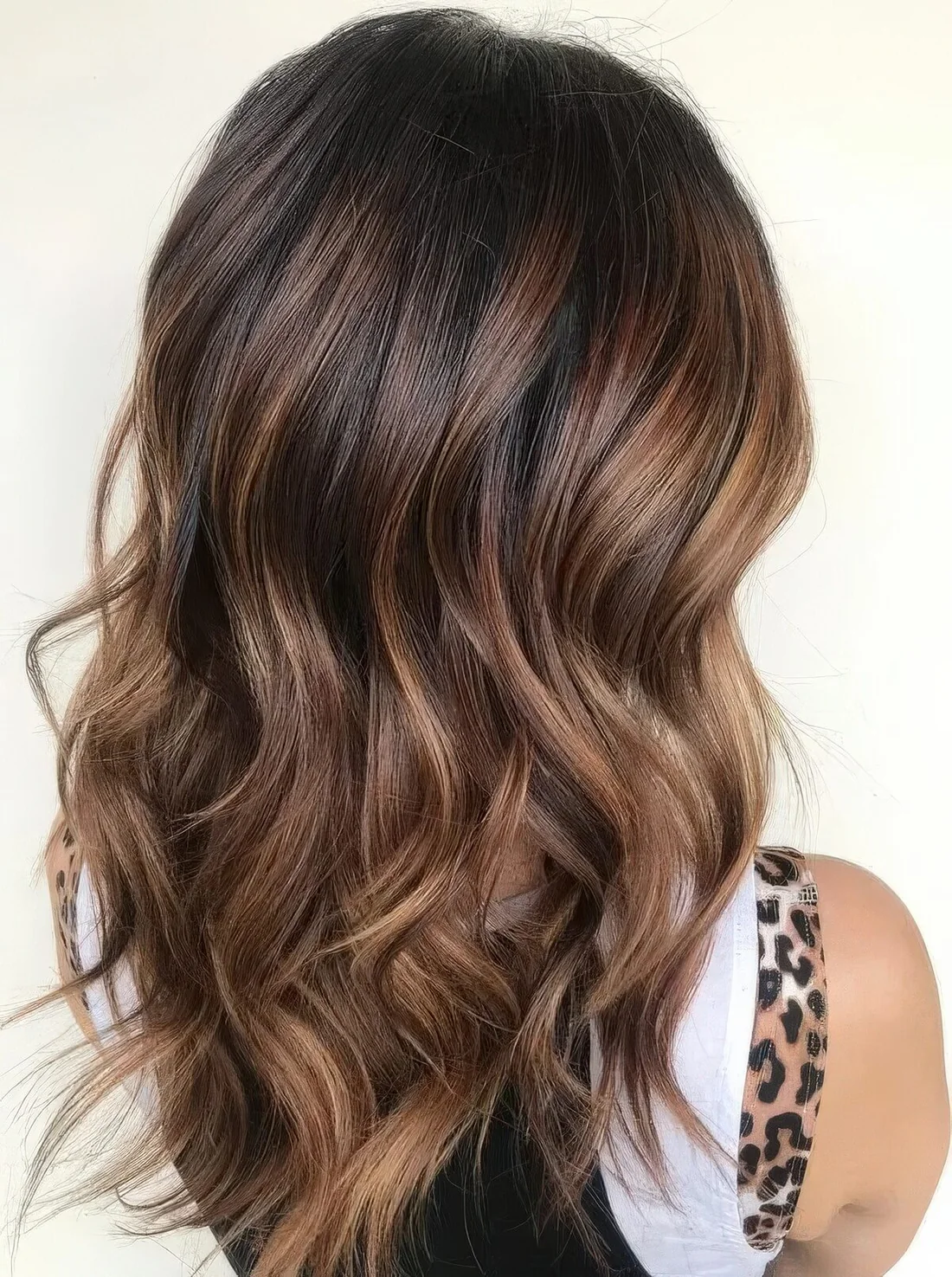 Long and wavy dark brown hair with caramel and honey blonde highlights.
