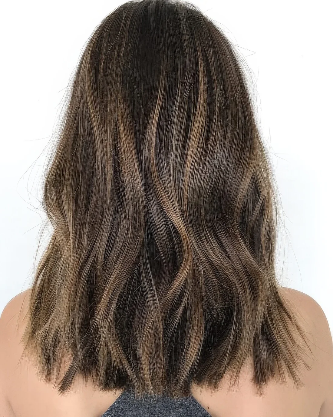 Long dark wavy hair with a delicate caramel balayage.
