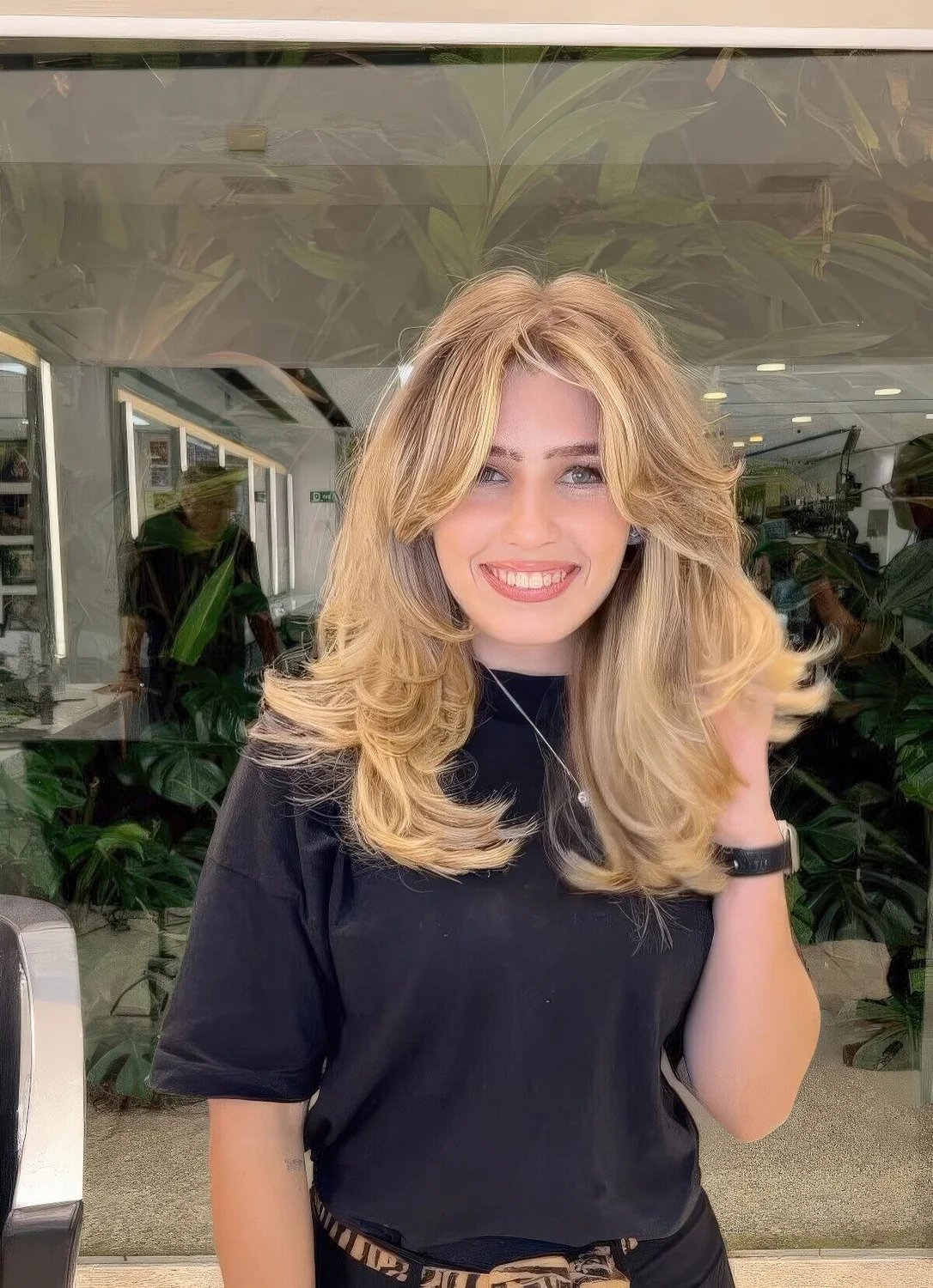 Voluminous blonde butterfly haircut with curtain bangs, wavy ends and a lot of dimension.
