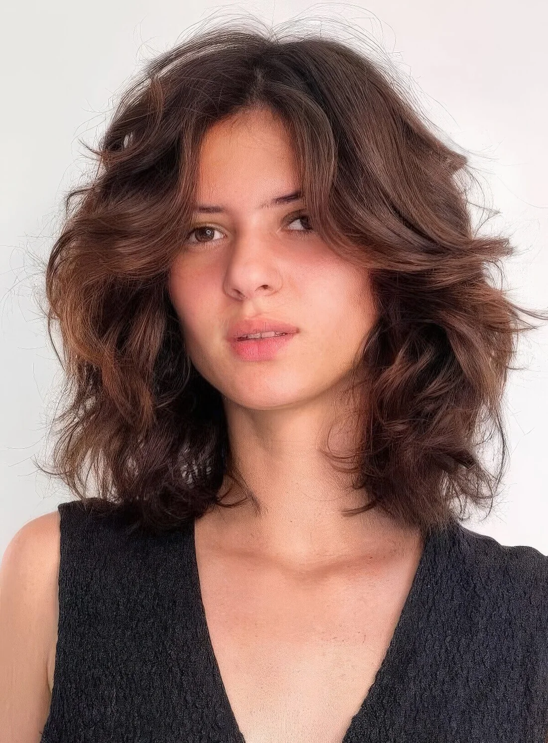 Dark brunette medium-length butterfly haircut on wavy hair, with a lot of dimension.