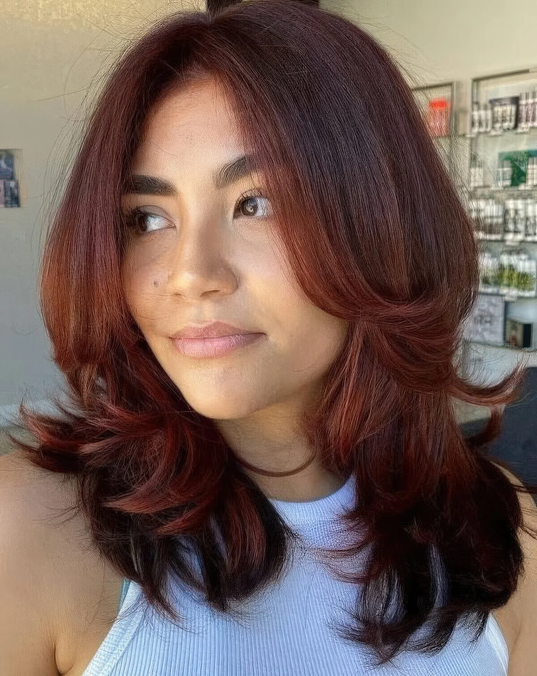 Auburn medium-length butterfly haircut with curved ends.