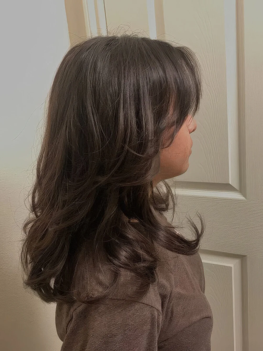 Brunette medium butterfly haircut with curled ends and a lot of volume.