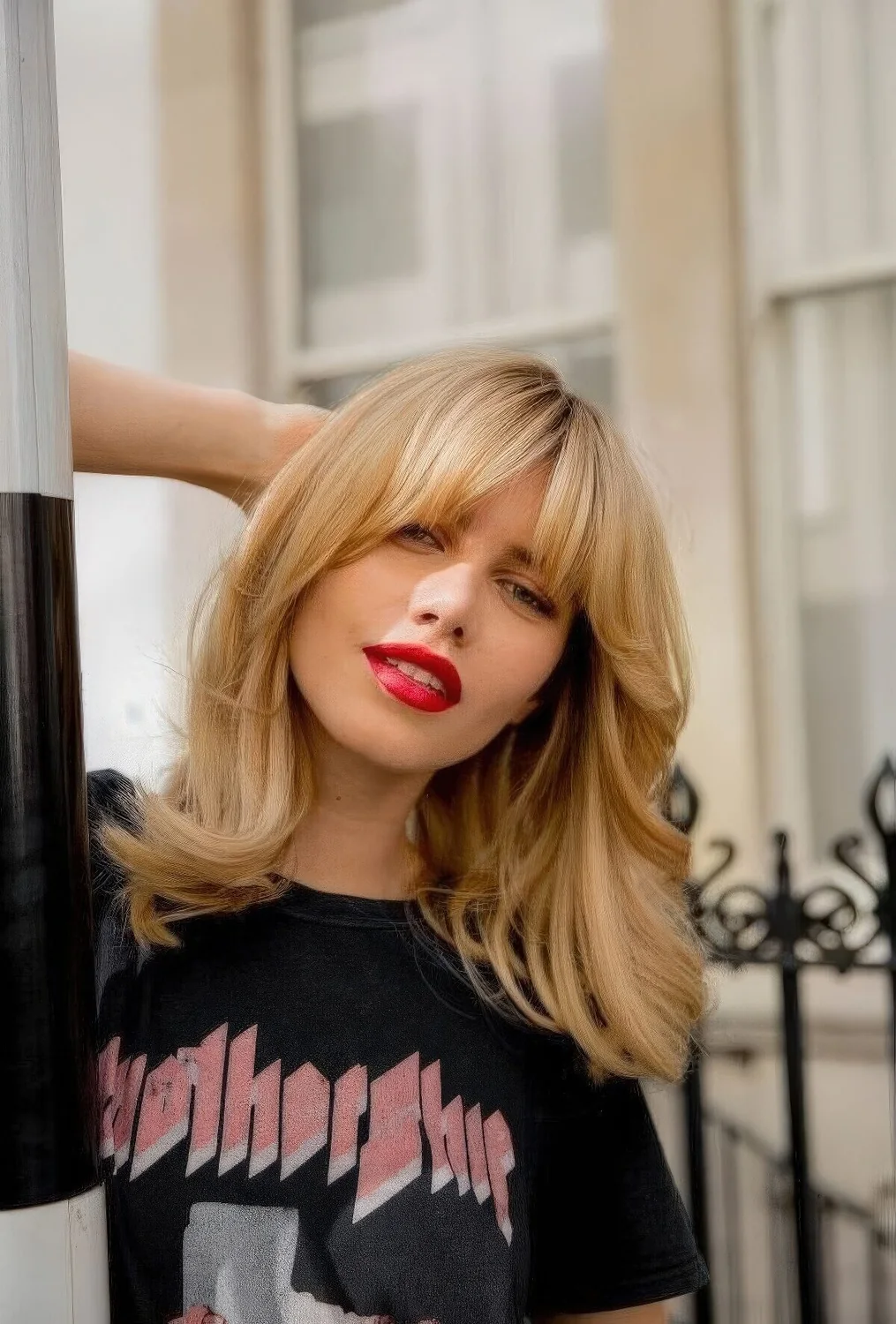 Medium blonde butterfly haircut with waves and bottleneck bangs.