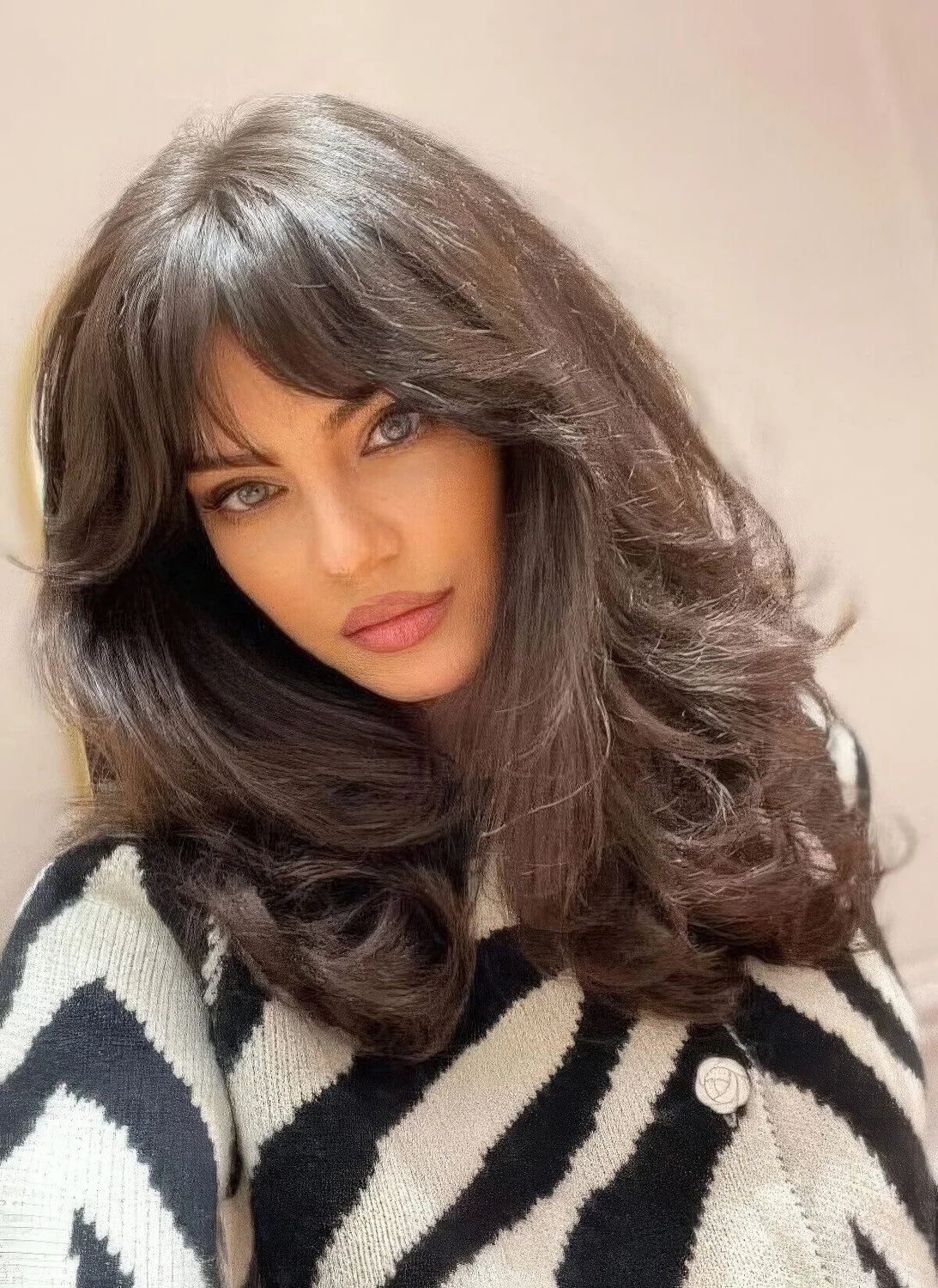 Dark brunette medium butterfly haircut on thick hair, with bottlneck bangs and waves.