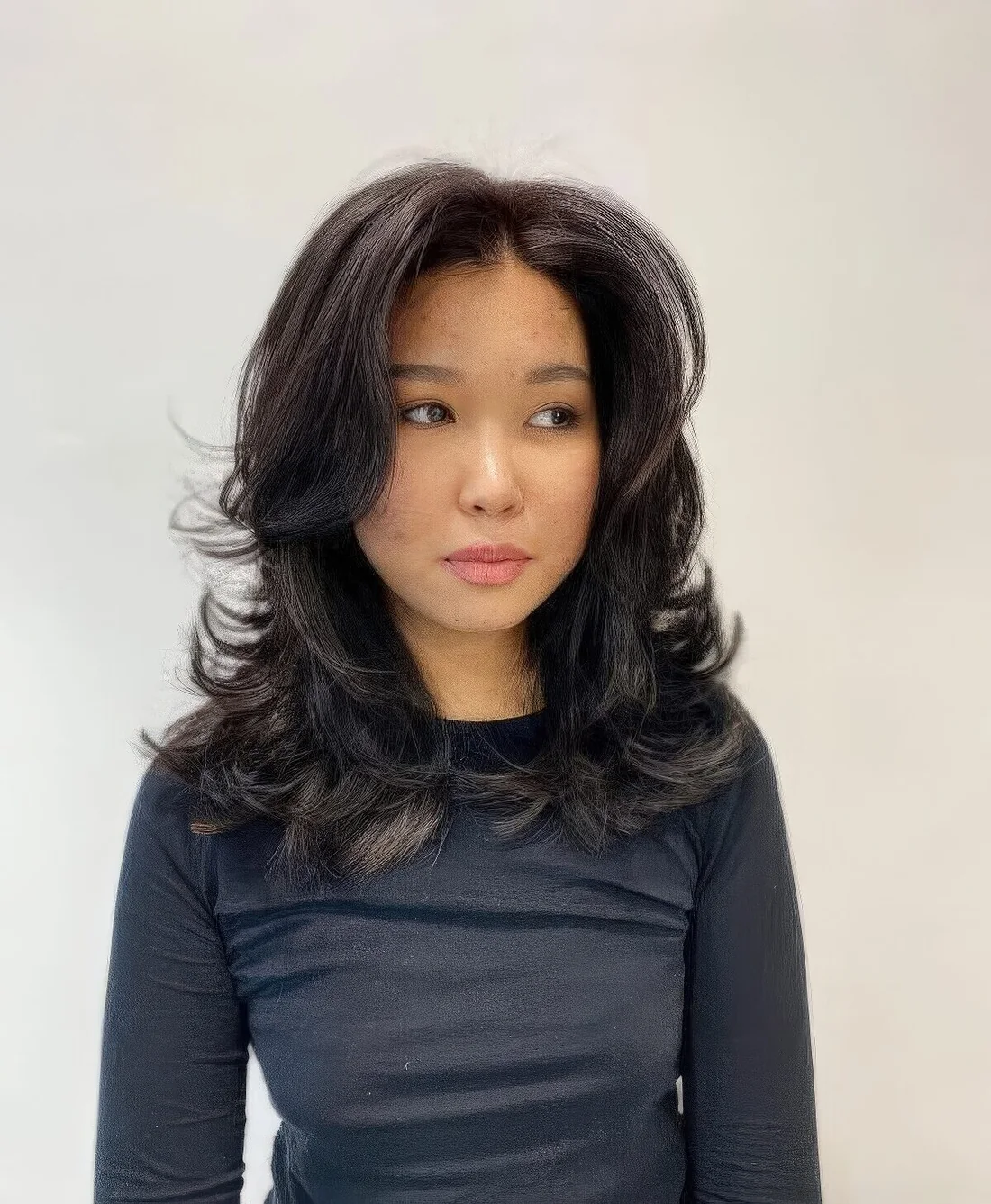 Black medium butterfly haircut with a lot of volume and curved ends.