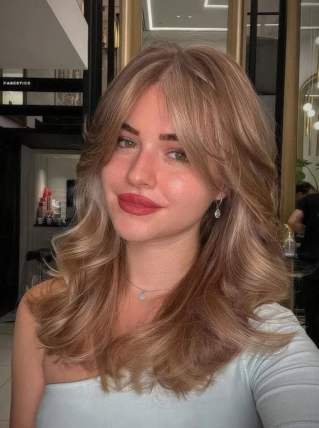 Bronde wavy hairstyle done on a butterfly haircut, with curtain bangs.