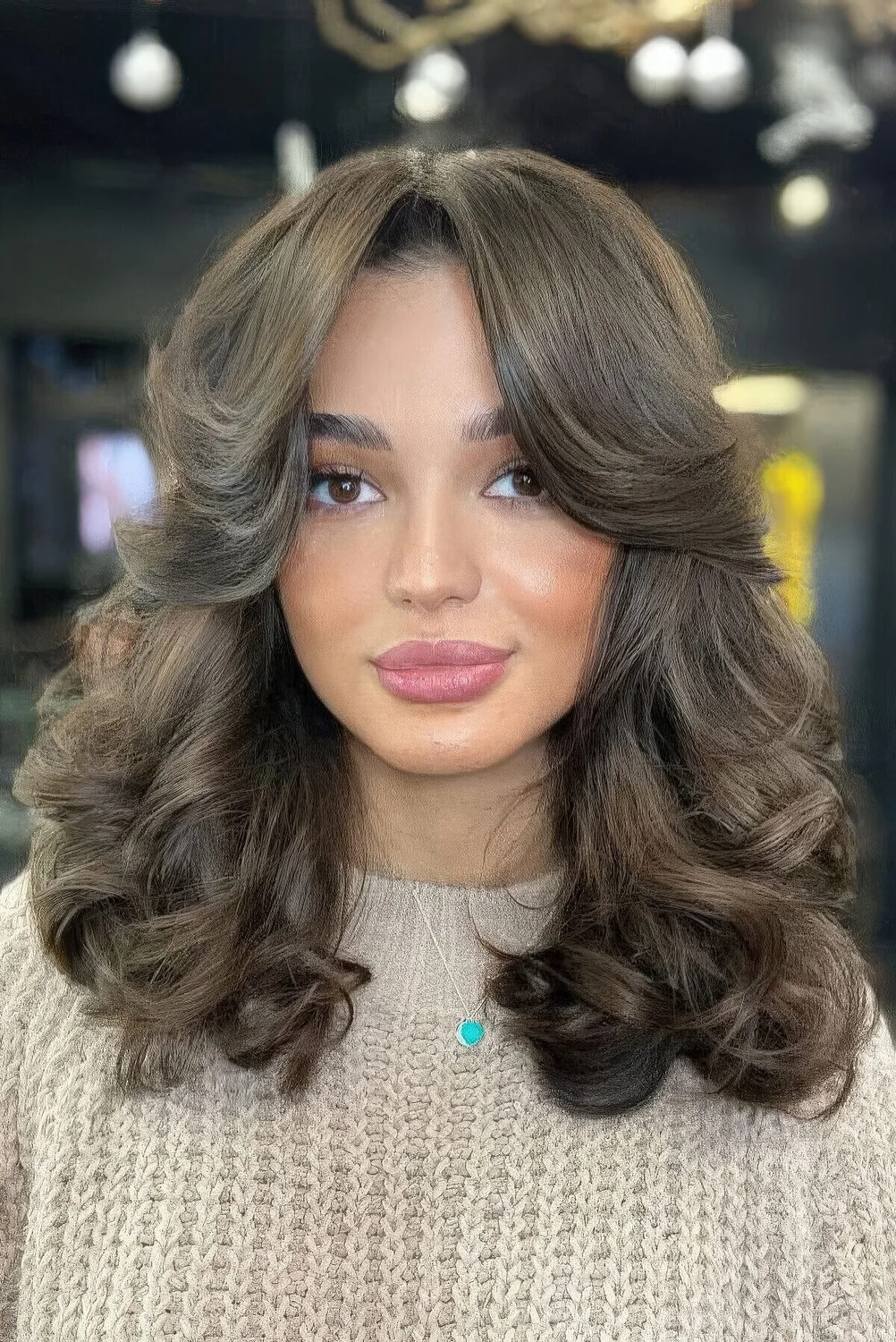 Brunette medium butterfly haircut with side bangs and curls.