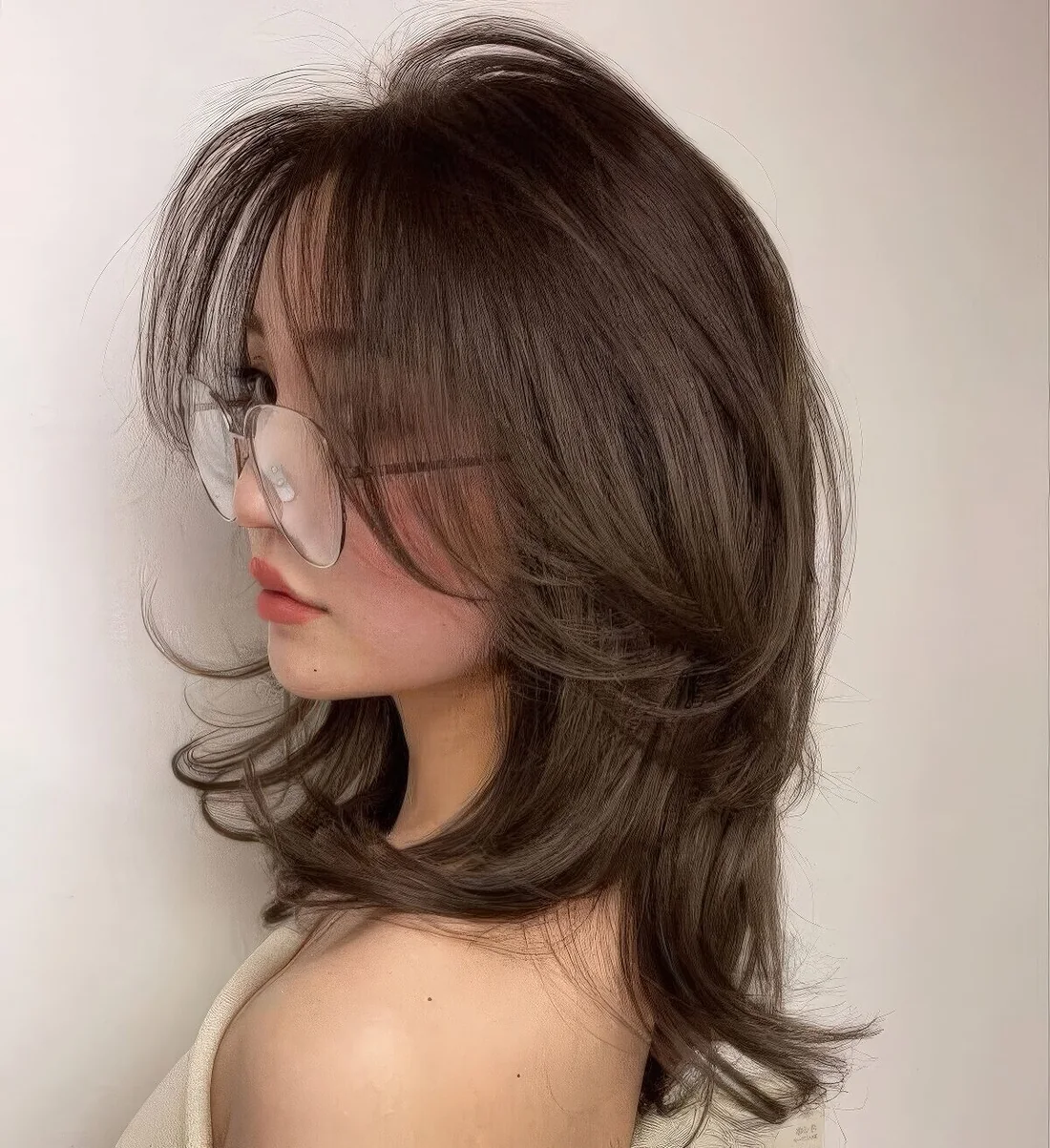 Medium brunette haircut with a lot of volume and wispy bangs plus curled ends.