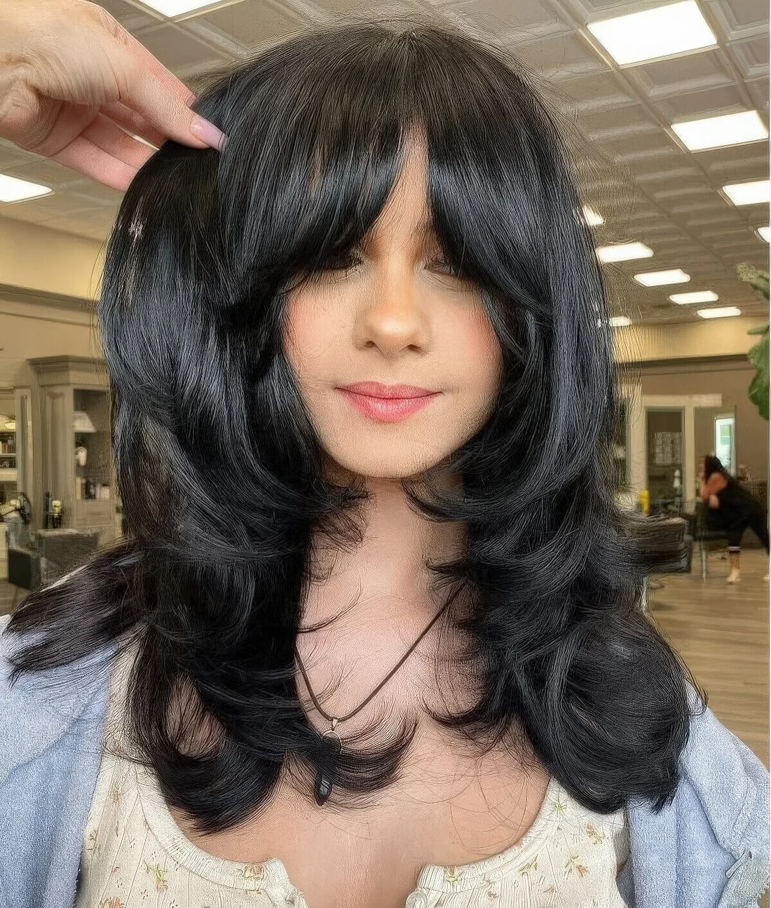 Medium black butterfly haircut with curtain bangs and curled ends and a shiny touch.