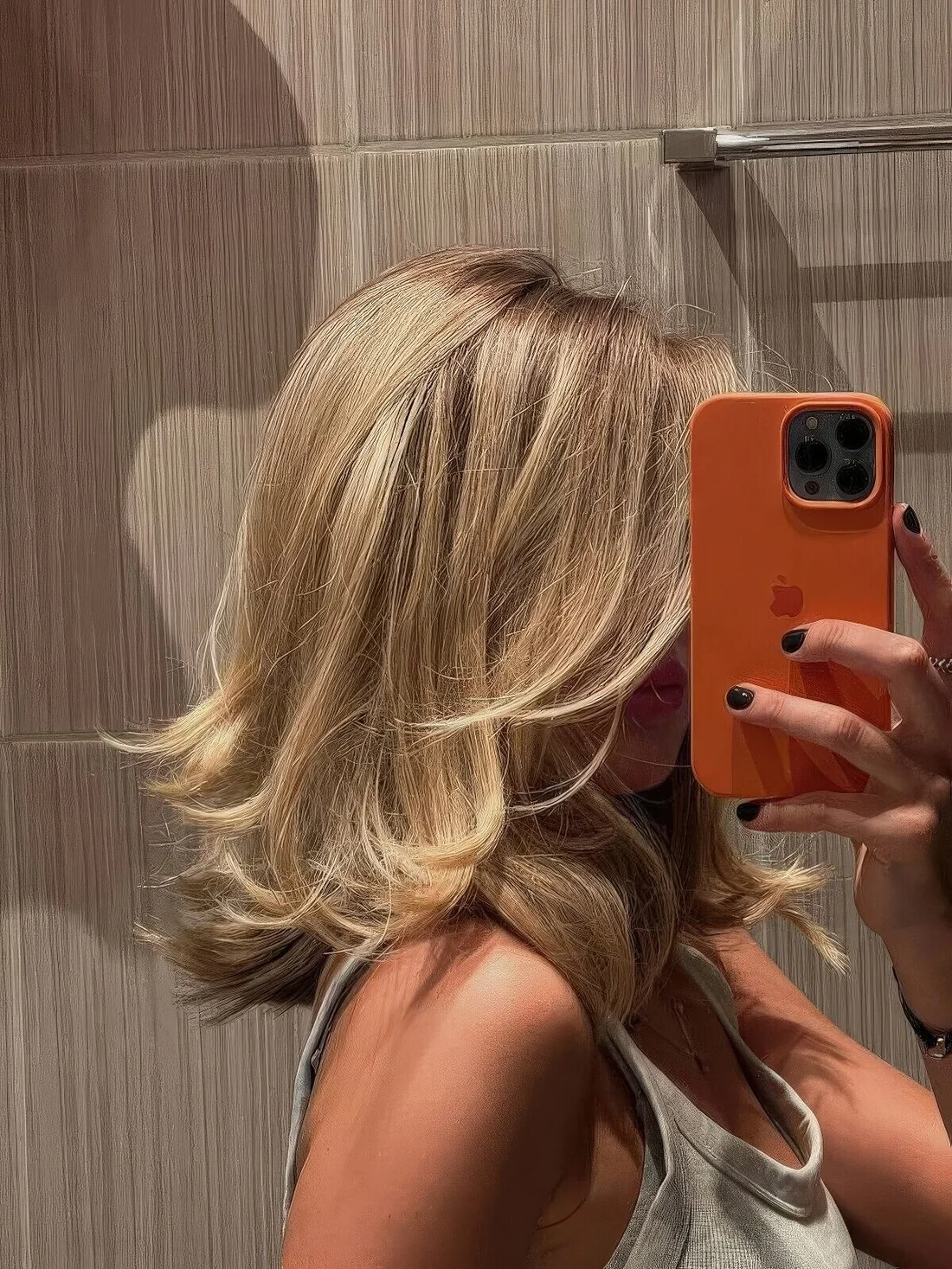 Medium blonde butterfly haircut with curled ends and a bit of texture and volume.