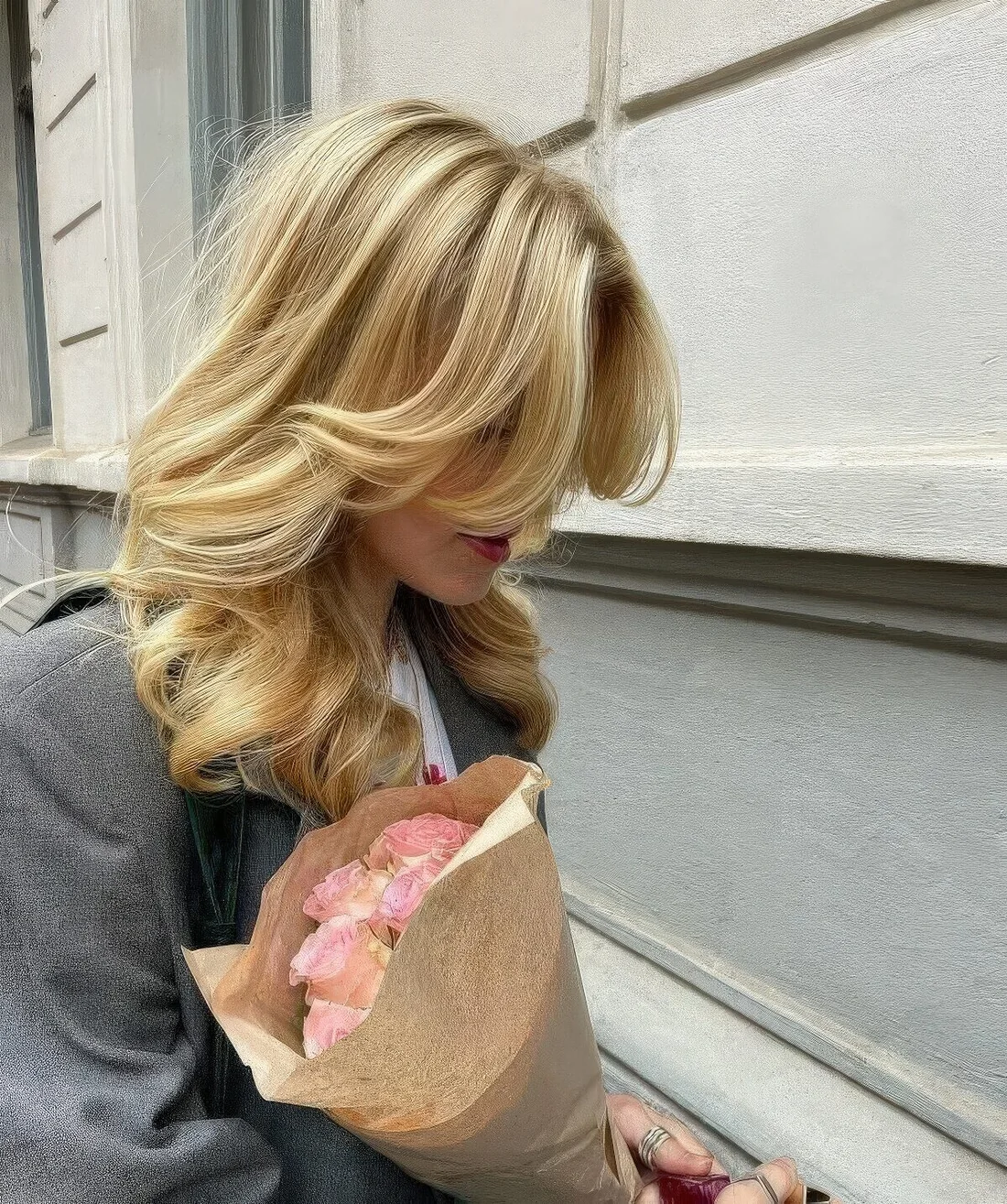Medium blonde butterfly haircut with curtain bangs and curls.