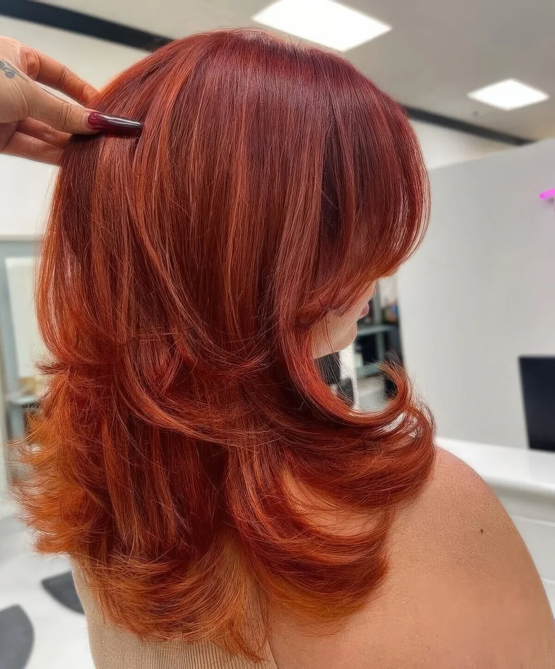 Medium butterfly haircut done in super bold red shades, with highlights and curled ends.