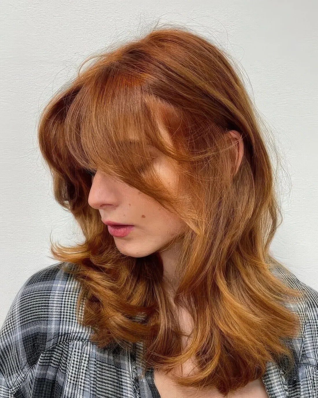 Medium butterfly haircut with some golden blonde highlights done in a super bold ginger color, it.
